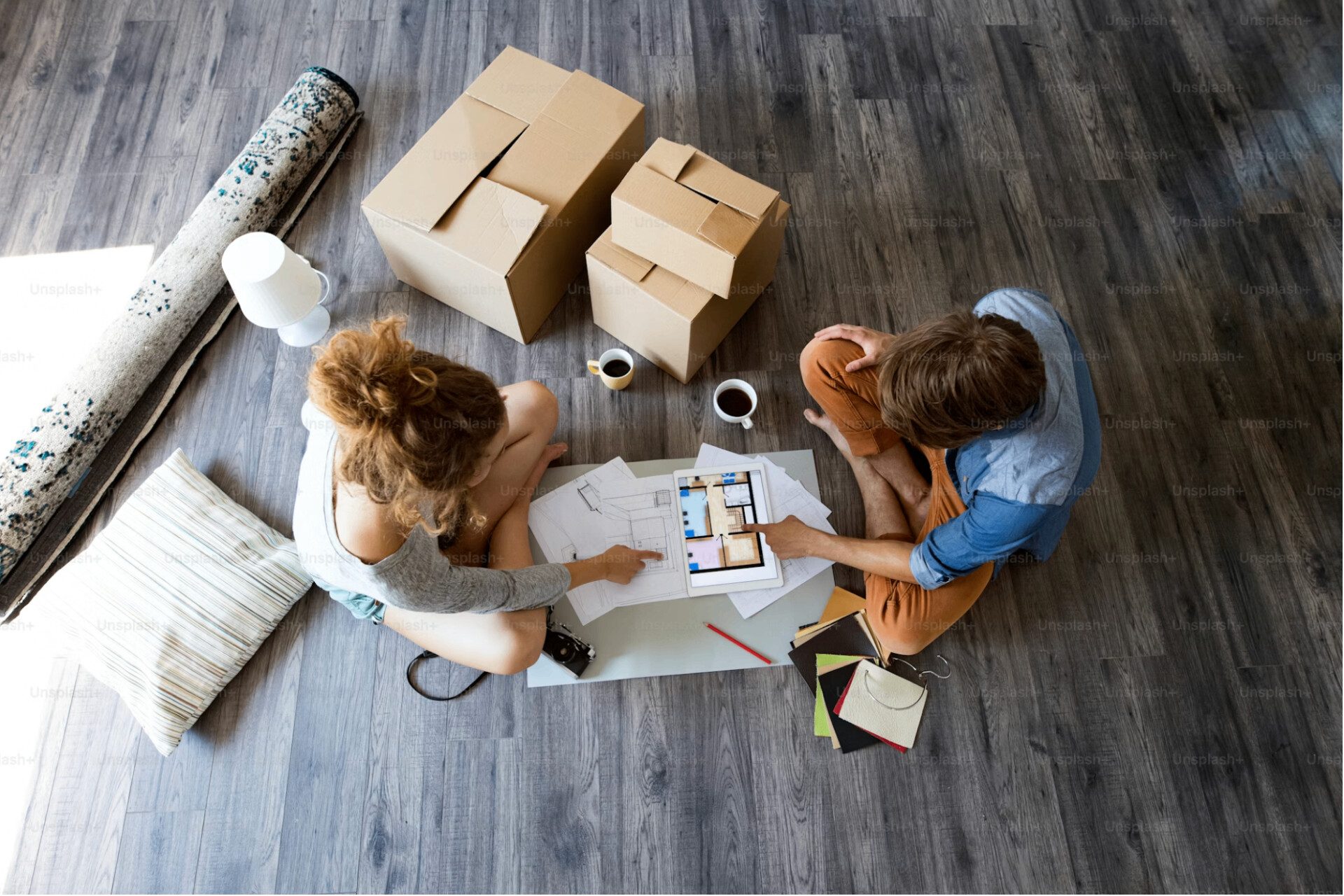 An Edmonton couple reviewing renovation plans and material samples on the floor of an empty rental